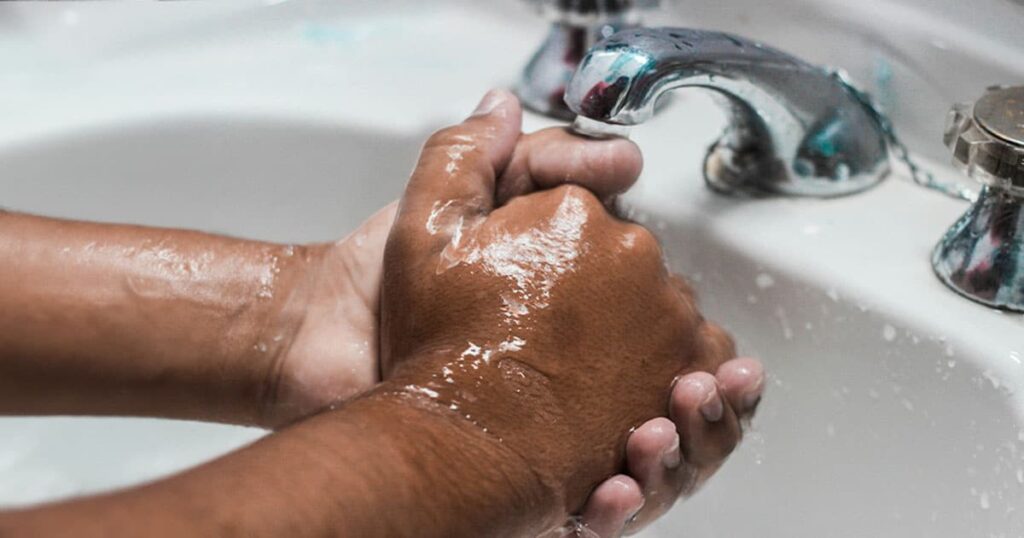 Hands checking a leaking faucet for water leaks