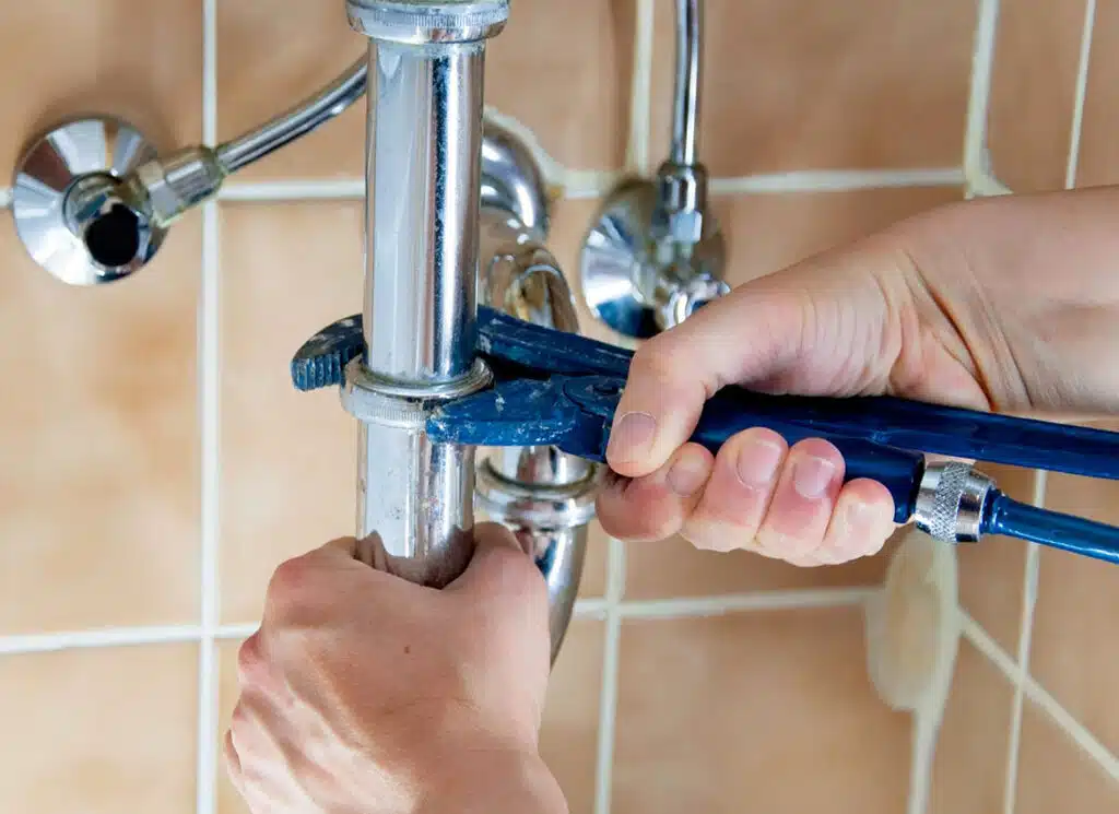 Plumber tightening a kitchen sink pipe connection