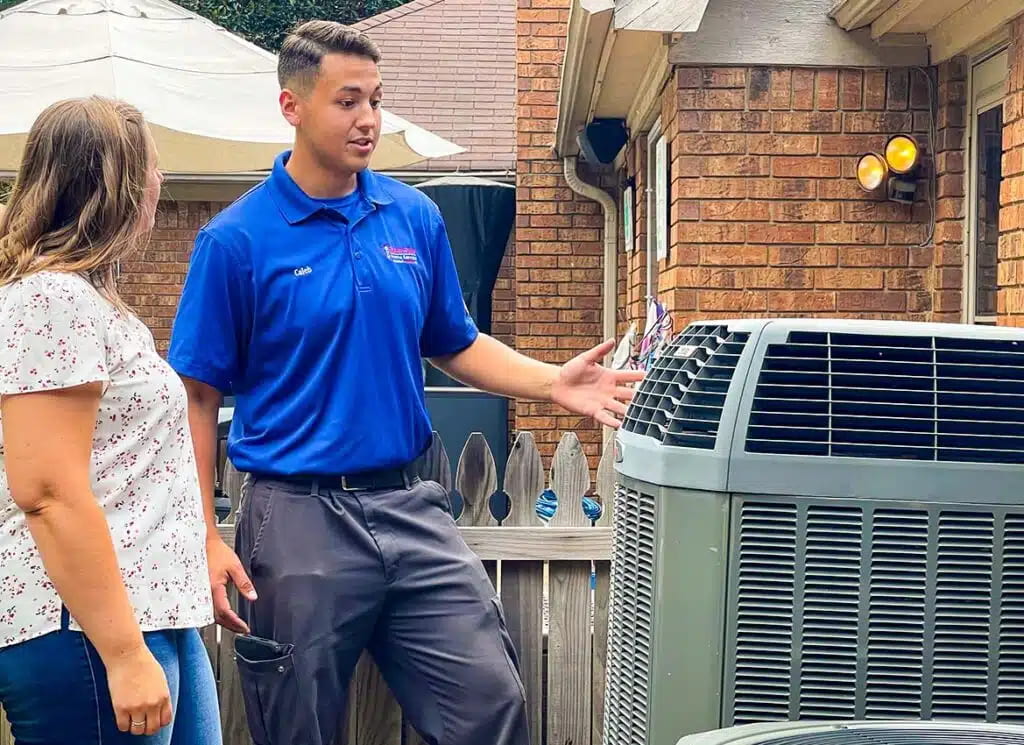 HVAC technician explaining an air conditioning system to a homeowner