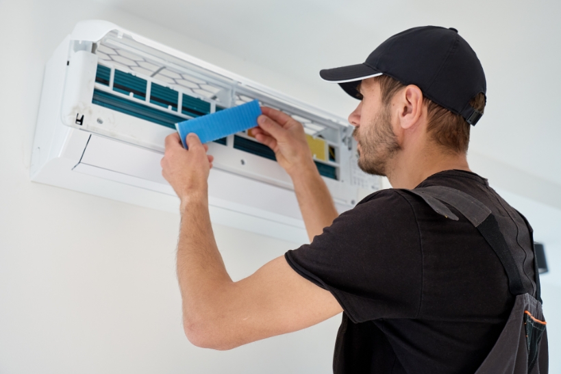 HVAC technician testing and inspecting the air filter in a ductless mini-split system.