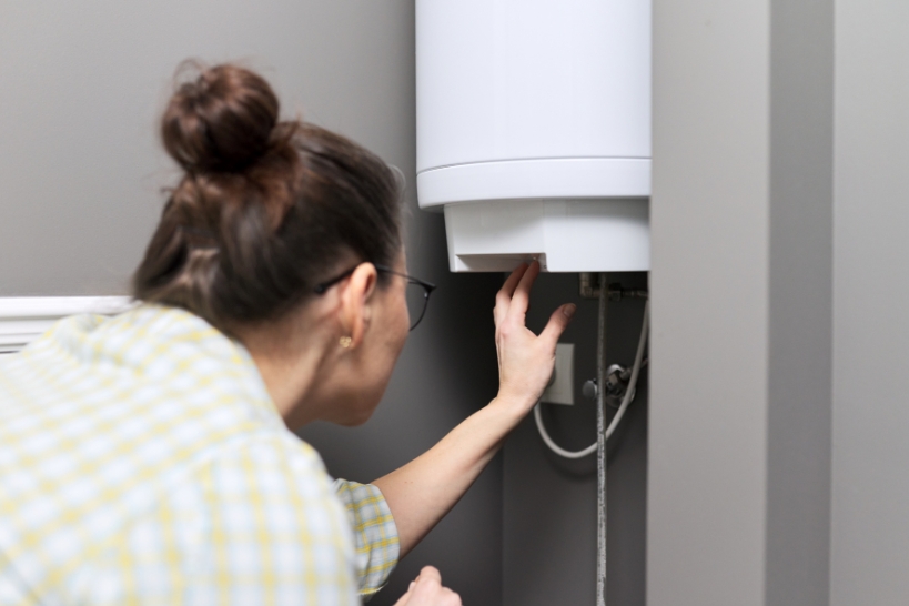 Homeowner checking a water heater that is making hissing or sizzling noises.